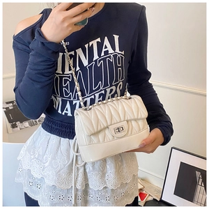 Detail of off-white quilted leather crossbody bag with silver chain strap and metal lock
