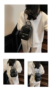 Close-up of black quilted patent leather mini backpack with silver chain and twist lock