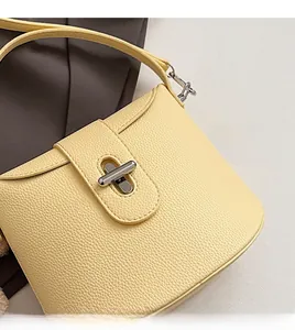 Close-up of cream yellow shoulder bag showing soft litchi grain texture and silver buckle