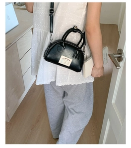Vue détaillée d'un mini sac bowling noir avec poignées et bandoulière réglable pour femme