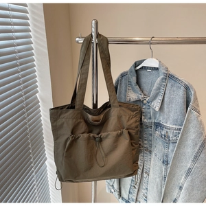 Detail view of military green nylon tote bag featuring a functional drawstring front pocket