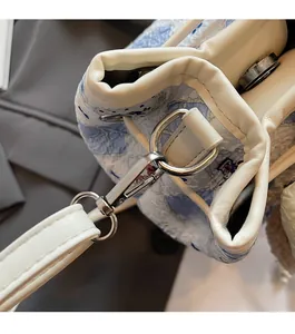 Detail of silver metal hook and leather strap on a blue and white patterned bucket bag