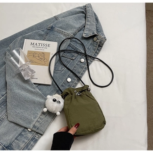 Mini olive green drawstring crossbody bag with fuzzy monster charm and long black strap