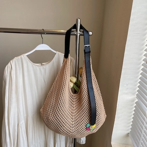 Detail of hand-woven crochet tote bag with black leather strap and floral accents