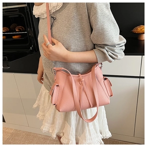 Pink lychee grain leather crossbody bag with drawstring knot and side pockets detail