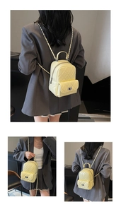 Detail view of mini quilted backpack in pale yellow with chain strap and metal turn-lock