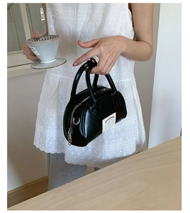 Détail d'un mini sac cabas noir brillant avec double poignée et étiquette blanche