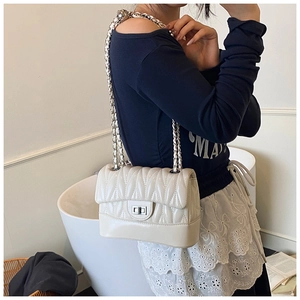 Detail of leaf-quilted cream leather shoulder bag with silver chain and twist-lock clasp