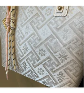 Detail of minimalist tote bag showing geometric meander pattern and woven rope texture
