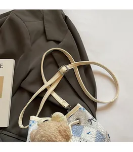 Blue and white plaid quilted bucket bag with adjustable strap and bear pendant detail