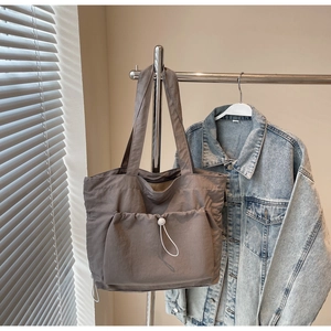 Detail of grey large tote bag showing drawstring pocket and nylon fabric texture