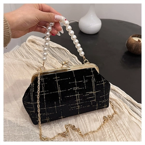 Détail du sac en velours noir avec imprimé grille dorée et poignée en perles élégante