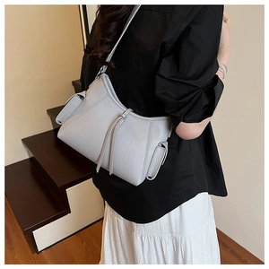 Detail of light blue pebble leather bag with fold-over side pockets and tassel accents