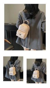 Detail view of a beige quilted mini backpack with silver metal chain straps on a model