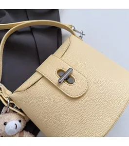 Close-up of light yellow lychee pattern bag with silver metal swivel lock and bear charm