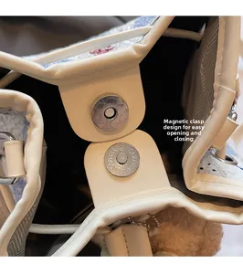 Detail of magnetic snap closure and leather stitching on white bucket handbag
