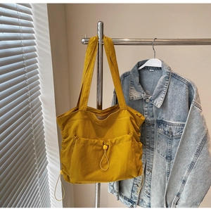 Detail of mustard yellow tote bag with drawstring pockets and adjustable buckle