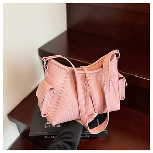 Detail shot of pink lychee textured leather bag showing side flap pockets and strap