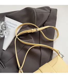 Detail of adjustable strap and lychee grain leather texture on a pale yellow bag