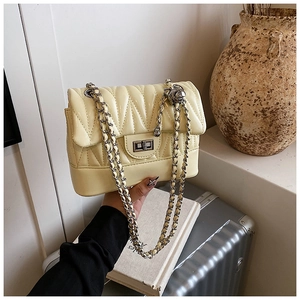 Detail of light yellow quilted shoulder bag with silver clasp and metal chain strap