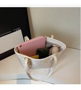 Top-down view of a spacious white tote bag interior with tablet, phone, and wallet
