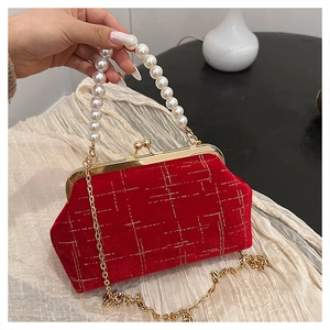 Détail d'un sac en velours rouge avec motifs dorés et élégante poignée en perles