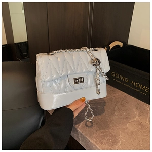 Close-up of light blue quilted leather bag with silver chain and metal ball charm