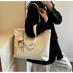 Close-up of beige tote bag with pebbled leather texture and embossed H.SHAN lettering