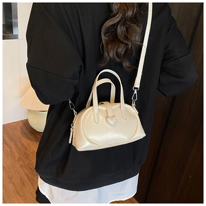 Detailed back view of a cream-white heart-shaped mini crossbody bag worn by a model