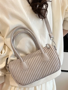 Minimalist beige pleated crossbody bag with a curved design and detachable strap
