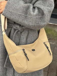 Minimalist beige half-moon crossbody bag with outdoor cord zippers and double front pockets