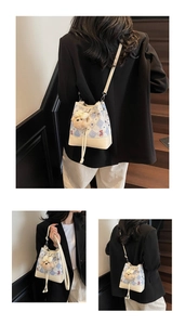 Detailed view of bucket bag with snowflake embroidery and plush bear charm accessory
