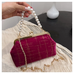 Détail du sac en velours magenta avec poignée en perles et bandoulière dorée