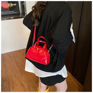 Red heart-shaped mini dumpling bag shown on model for size and style reference