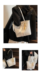 Detailed view of white geometric textured tote bag with a decorative tassel pendant