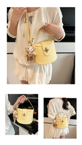 Detail of yellow saddle bag featuring lychee texture leather and a plush bear pendant