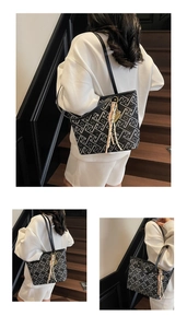 Detail of black woven tote bag with white jacquard pattern and pink tassel charm