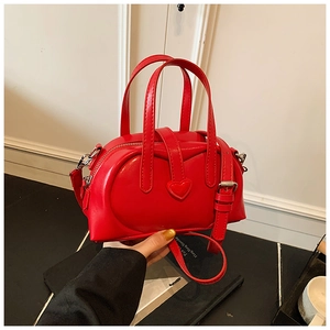 Detail of red heart-embossed handbag with silver lock and adjustable shoulder strap