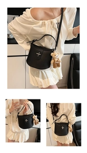 Detail view of black pebble leather bucket bag with silver clasp and bear charm
