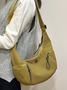 Mustard yellow nylon crescent crossbody bag with zipper pockets worn by a model