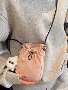 Pink nylon mini drawstring crossbody bag with a cute monster plush charm on shoulder