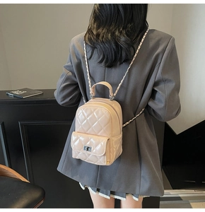 Detail of beige quilted mini backpack featuring chain straps and silver metal turn-lock