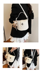 Close-up of white lychee leather bucket bag featuring a silver twist lock and bear charm