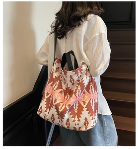 Detail of large canvas tote bag with orange geometric patterns shown on a model