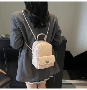 Detail of a quilted mini backpack in beige with chain straps and metallic clasp closure