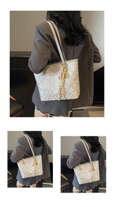 Detail of light grey tote bag with geometric floral texture and tassel charm detail