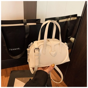Detailed view of off-white heart-shaped decor on a sleek synthetic leather handbag