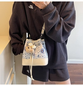 Detail of drawstring bucket bag with floral patterns and a cute teddy bear charm