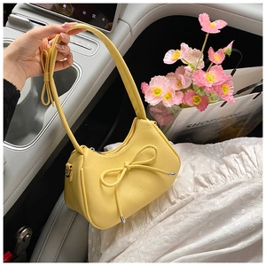Detailed macro view of yellow dumpling bag featuring litchi grain and bow drawstring