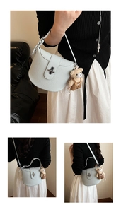 Detail of light blue lychee pattern underarm bag with silver twist lock and bear charm